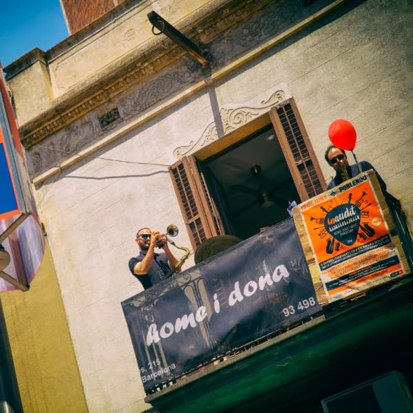 Foto de un músico tocando la trompeta en un balcón de una esquina del barrio de Poblenou