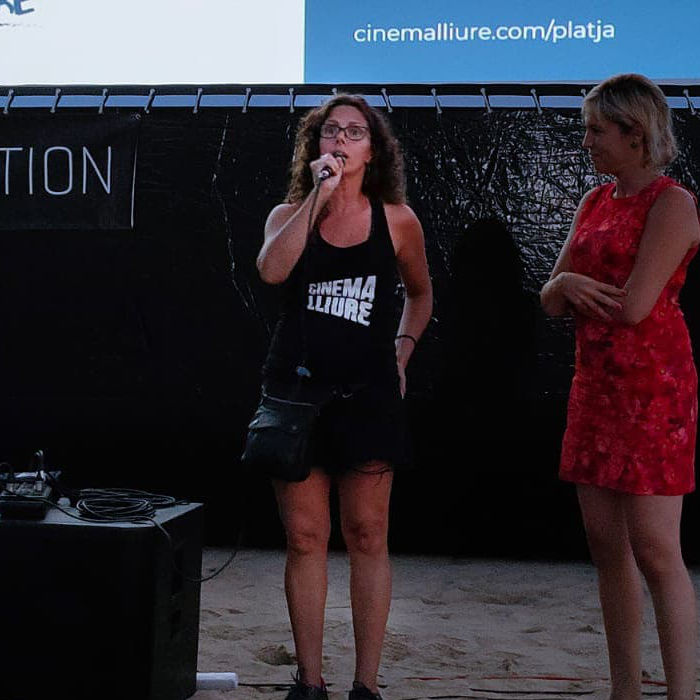 Mujer hablando al micrófono presentando una película en la playa