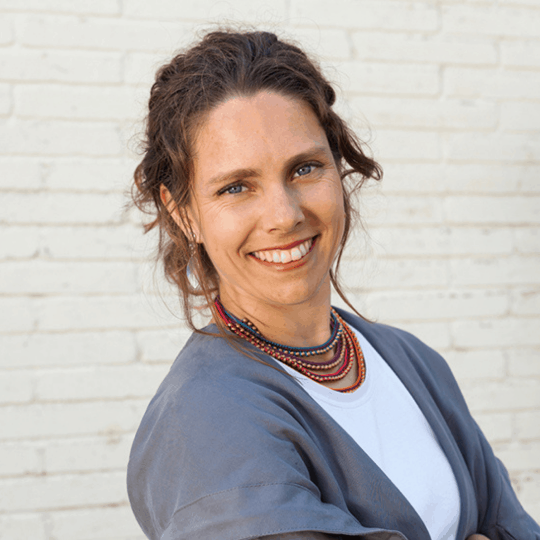 Foto Juliana Spadano - mujer sonriendo, pelo recogido, fondo de pared blanca.